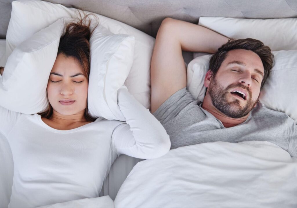 Paar im Bett als Symbolbild für Schnarchen, Atemaussetzer und gestörten Schlaf