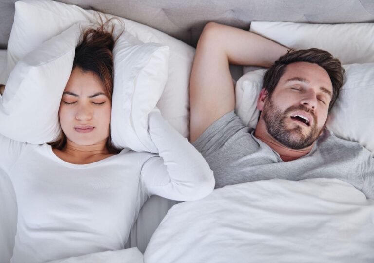 Paar im Bett als Symbolbild für Schnarchen, Atemaussetzer und gestörten Schlaf
