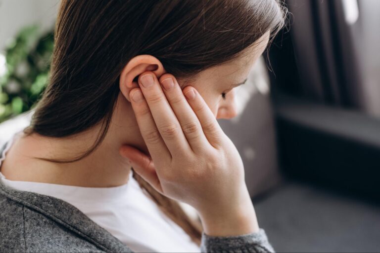 Frau hält sich Ohr als Symbol für einen Hörsturz