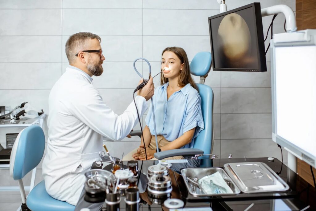 Ein HNO-Arzt untersucht die Nase einer Patientin mittels Endoskopie in seiner Praxis zur Abklärung von Beschwerden.